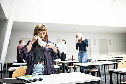 Foto: Studierende setzt eine FFP2-Maske während der Lehrveranstaltung auf 
