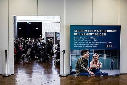 Foto: Blick in einen Veranstaltungsraum der Beruflichen Hochschule Hamburg, in dem Menschen sitzen.