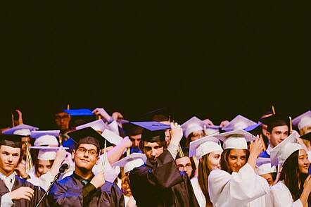 Foto: Masterabsolventinnen und Masterabsolventen legen die Quaste ihres Hutes von rechts nach links