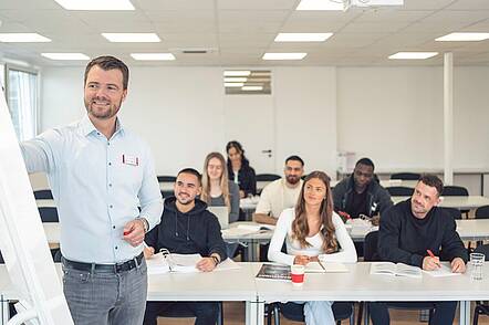 Foto: Lehrender erläutert Forschungsergebnisse an der Tafel. 
