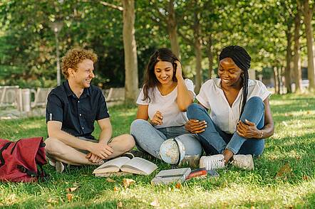 Foto: Studierende der Universität Erfurt sitzen in einem Park und unterhalten sich