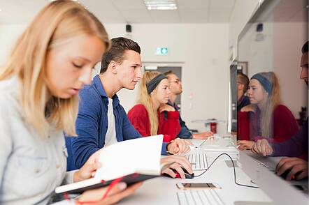 Foto: Studierende sitzen vor Computern und arbeiten. 