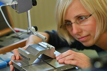 Foto: Eine Studentin bearbeitet und prüft ein Stück Metall