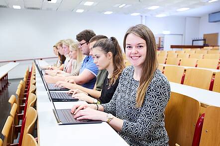 Foto: Studenten der Hochschule Kehl sitzen auf den Banken im Hörsaal an ihren Laptops.
