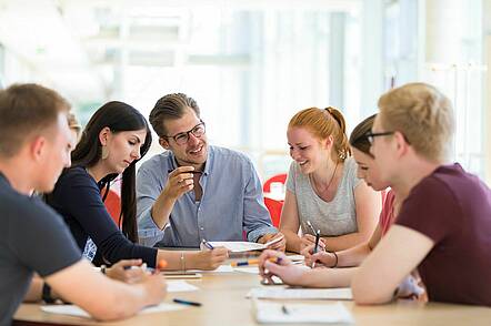 Foto: Studierende sitzen an der Lerninsel der EBZ Business School in Bochum und unterhalten sich.