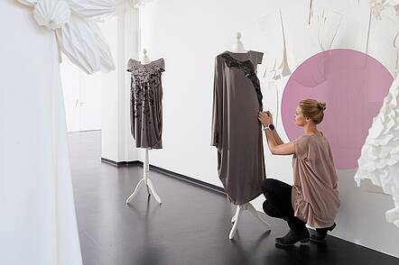 Foto: Eine Studierende im Studiengang Modedesign steckt ein Kleid ab.