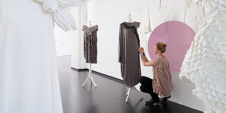 Foto: Eine Studierende im Studiengang Modedesign steckt ein Kleid ab.