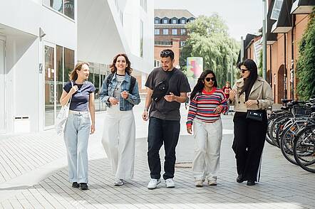 Foto: Internationale Studierende an der Universität Kassel gehen gemeinsam über den Campus.