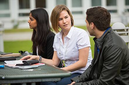 Foto: Studierende der HWG Ludwigshafen sitzen auf dem Campus und unterhalten sich.