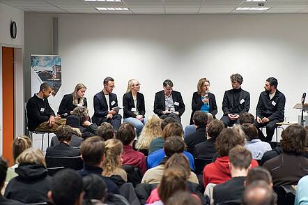 Foto: Teilnehmende an einer Podiumsdiskussion sitzen zusammen