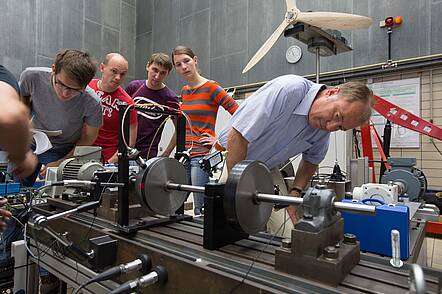 Foto: Studenten mit Ihrem Dozenten hinter einem Getriebe
