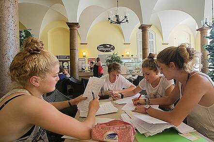 Studierende sitzen in der Caféteria der Universität Bonn und lernen zusammen.