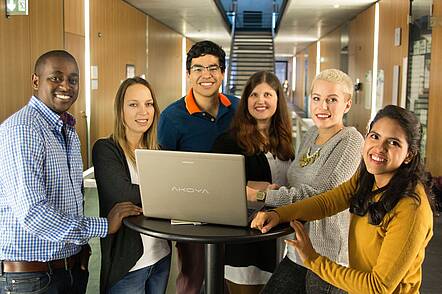 Studierenden Gruppe steht um einen Laptop