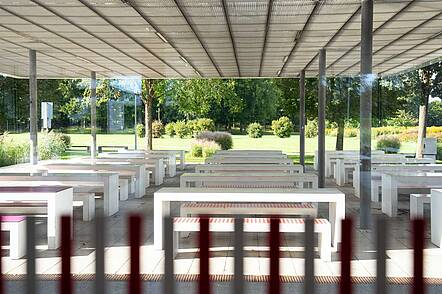 Foto: Überdachter Sitzbereich im Grünen mit vielen Bänken und Tischen 