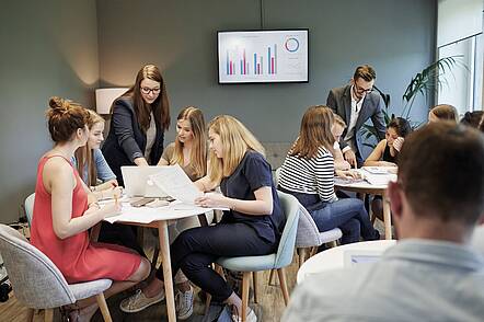 Foto: Studierende der CBS sitzen zusammen, arbeiten am Laptop und sichten Unterlagen