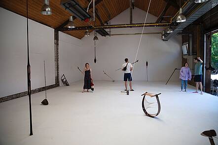 Foto: Studierende betrachten eine Kunstaustellung in einem Atelier