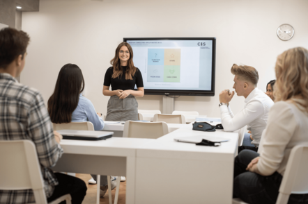 Foto: Eine Dozentin spricht vor Studierenden in einer Seminarsituation.