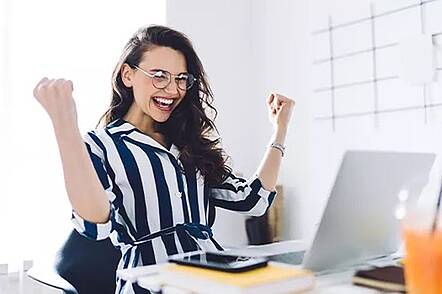 Foto: Eine Studentin sitzt am Schreibtisch und blickt in einen Laptop