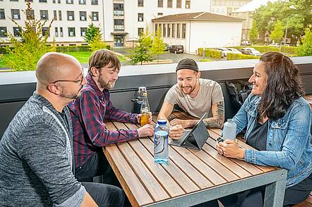 Foto: Studierende der Evangelischen Hochschule Dresden sitzen zusammen an einem Tisch und blicken auf einen Laptop