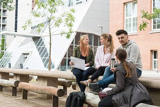 Foto: Studierende sitzen auf dem Campus Berliner Tor der HAW Hamburg und unterhalten sich