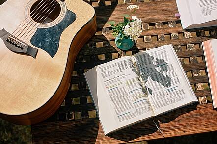 Foto: Blick auf einen Tisch, auf dem eine Gitarre und eine aufgeschlagene Bibel liegen
