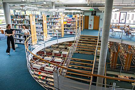 Foto: Blick in die Bibliothek der Universität Augsburg mit Bücherregalen und Arbeitsplätzen