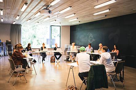 Foto: Studierende der Zeppelin Universität sitzen in einem Seminarraum im Stuhlkreis und diskutieren miteinander