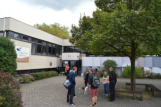 Foto: Studierende vor dem Eingang zum Lehrgebäude der Theologischen Hochschule Reutlingen