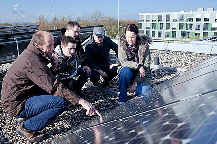 Foto: Dozent und Studierende sprechen auf dem Dach über die Solaranlage