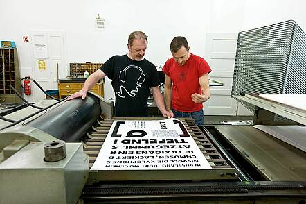 Foto: Studierender und Dozent besprechen die Arbeit in der Druckwerkstatt