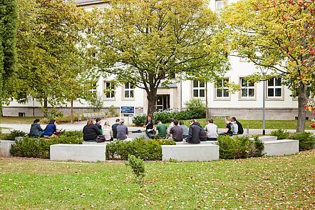 Foto: Eine Gruppe Studierender sitzt auf dem Campus der Universität Erfurt