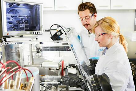 Foto: Zwei Personen in weißen Kitteln arbeiten in einem Labor.