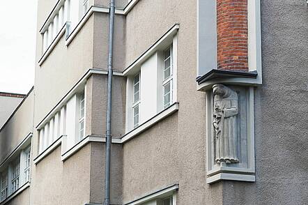 Foto: Gebäudeansicht der Katholischen Hochschule für Sozialwesen Berlin mit kleiner Statue an der Hauswand.
