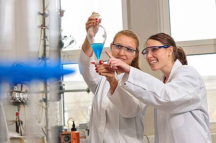 Foto: Zwei Studentinnen im Labor betrachten eine Flüßigkeit im Reagenzglas