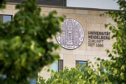 Foto: Blick auf das Gebäude der Universität Heidelberg mit großem Logo.
