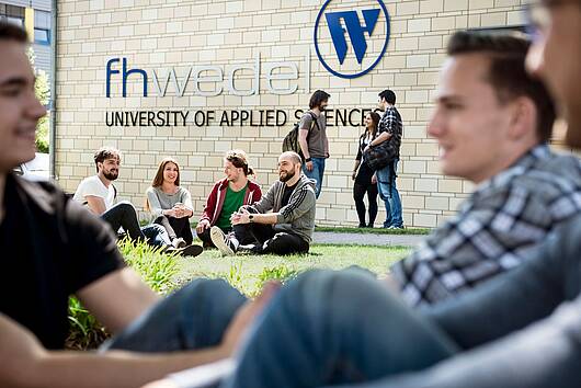 Foto: Gruppe von Studierenden sitzen auf dem Campus 