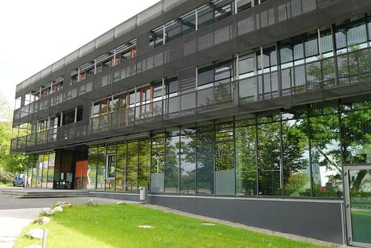 Foto: Blick vom Campus auf das Hauptgebäude der Steinbeis Hochschule mit großer Glasfront und dunkler Fassade