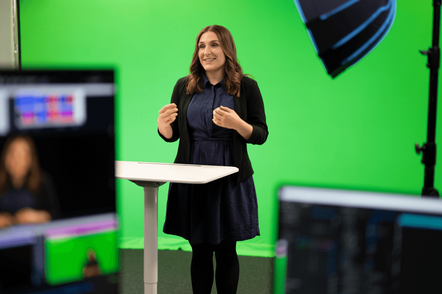 Foto: Eine Frau steht moderierend vor einem Greenscreen.