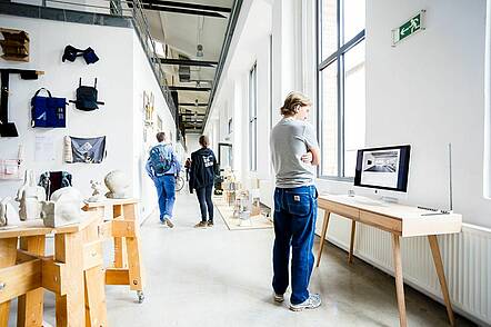 Foto: Studierende der Hochschule der Bildenden Künste Essen betrachten ausgestellte Projekte in den Hochschulräumlichkeiten.