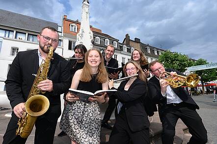 Studierende des Lehramts der HfM Saar (Foto: Iris M. Maurer) Foto: Eine Gruppe Studierende spielen Instrumente vor einem Brunnen auf einem öffentlichen Platz