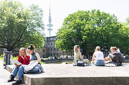 Foto: Studenten sitzen auf dem Campus in Gruppen zusammen.