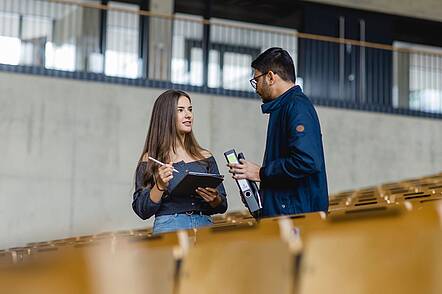 Foto: Studierende der Universität Koblenz stehen im Hörsaal und unterhalten sich. 