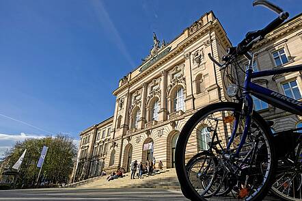 Foto: Blick auf das Hauptgebäude der Uni Würzburg am Sanderring. Im Vordergrund stehen Fahrräder.