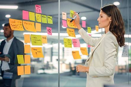 Studierende bei Konzeption (Foto: International School of Management) Foto: Studierende sortiert beschriftete Post-Its an Fenster.