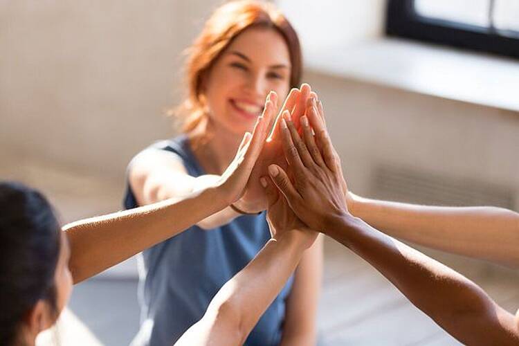 Foto: Studentinnen stehen im Kreis und geben sich ein gemeinsames High-Five