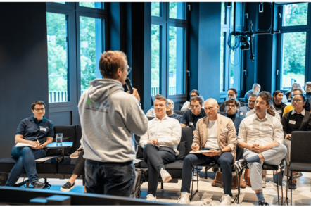 Foto: Eine Veranstaltung der Tomorrow University of Applied Sciences auf der Personen in Stuhlreihen zusammen sitzen.