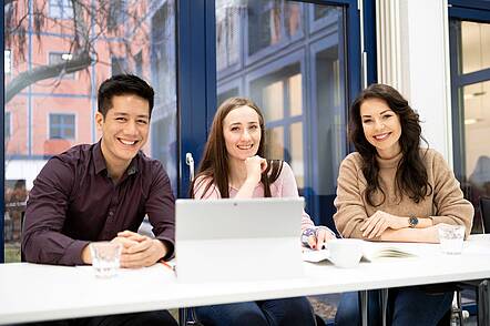 Foto: Studierende sitzen mit Laptop an einem Tisch