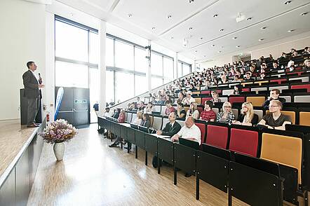 Foto: Studierende sitzen im Hörsaal und folgen einer Vorlesung.