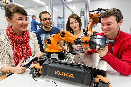 Foto: Foto: Studierende der Automatisierungstechnik und Robotik programmieren einen Roboter