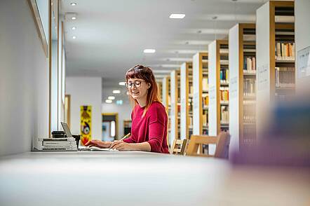 Foto: Eine Studentin der Evangelischen Hochschule Dresden macht sich Notizen in der Bibliothek